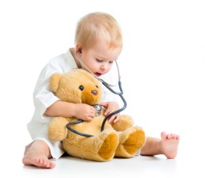 Adorable child with clothes of doctor and teddy bear over white